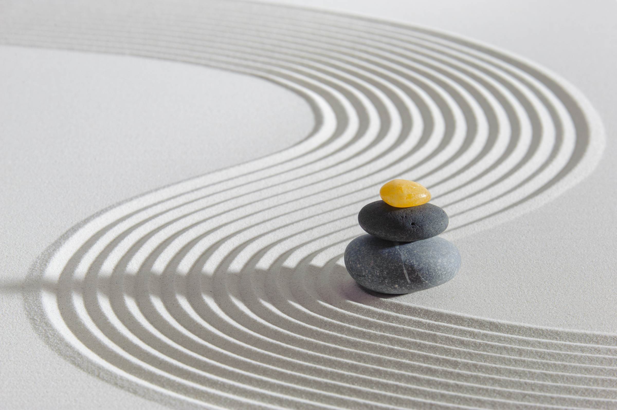 Zen-tuin met gestapelde stenen en golvende zandpatronen die rust en helderheid symboliseren, ter ondersteuning van een energetische hypnose demo.