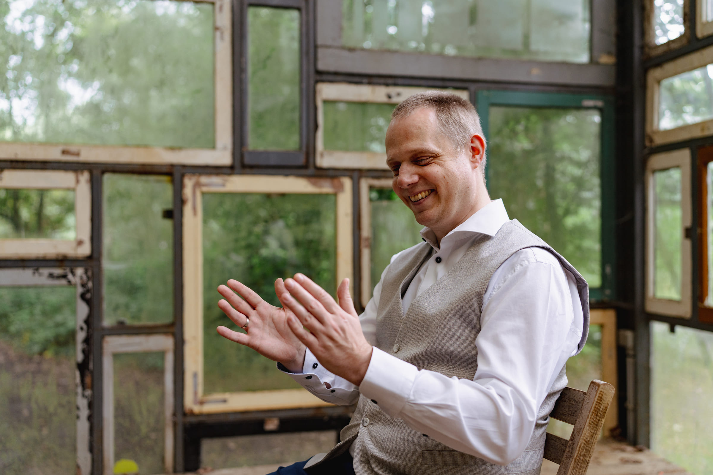 Maarten Wauters lachend en in zichzelf gekeerd zittend, symboliseert de innerlijke rust en het vertrouwen dat hij ontwikkelde tijdens zijn persoonlijke transformatie van een rationele ICT-achtergrond naar het begeleiden van anderen met hypnose en healing.
